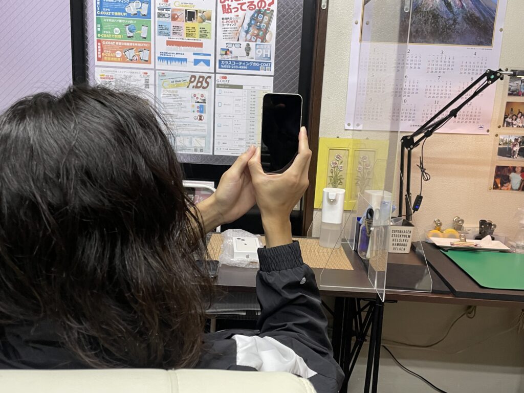 ガラスコーティング施工後のiPhone 13 miniを確認するお客様